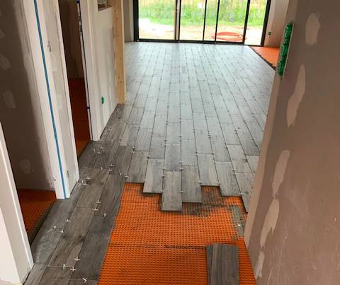 Pose de carreaux de carrelage imitation parquet et natte de désolidarisation sur plancher bois pour une maison à Gujan-Mestras.